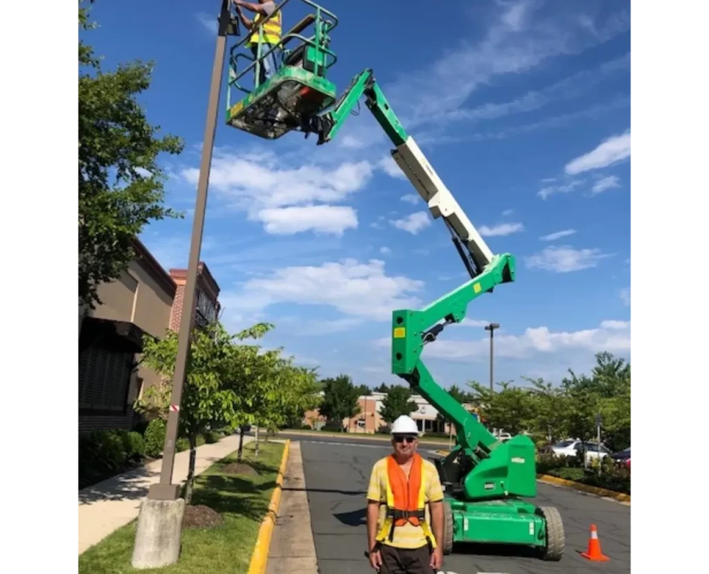 Electrician working at height using a green lift to install or repair a street light, part of SparkWise Electric's trusted services in Gainesville, VA.