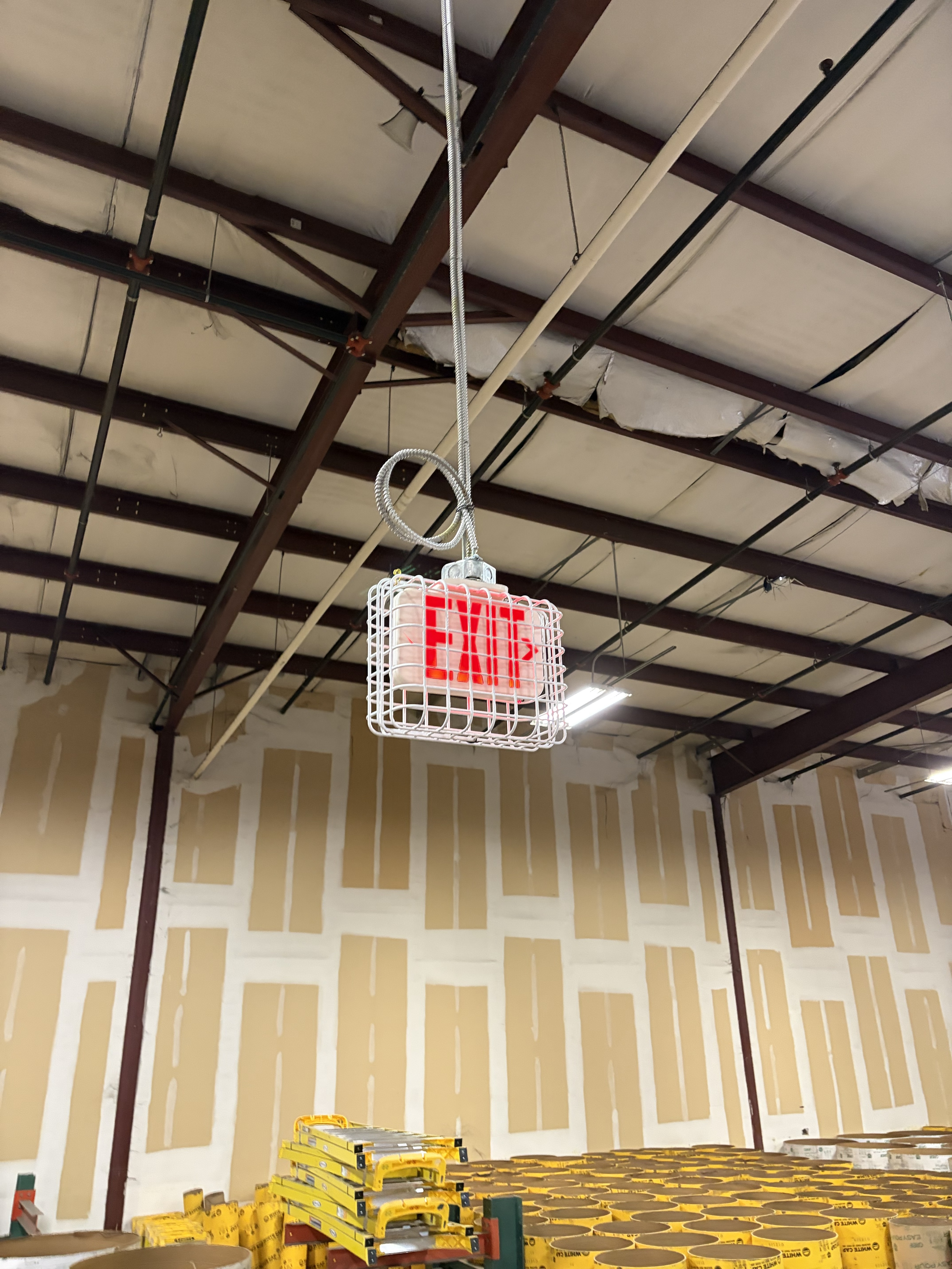 LED exit sign installed in a commercial warehouse along an egress path by SparkWise Electric