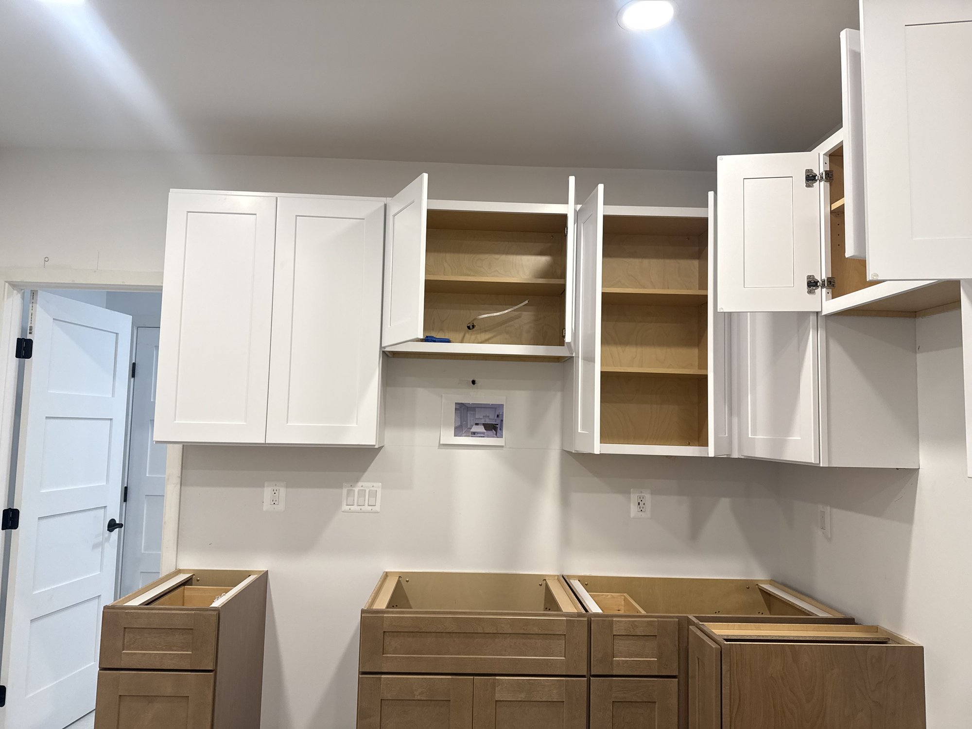 Kitchen cabinets during electrical rough-in with switch bank and recessed lighting installed