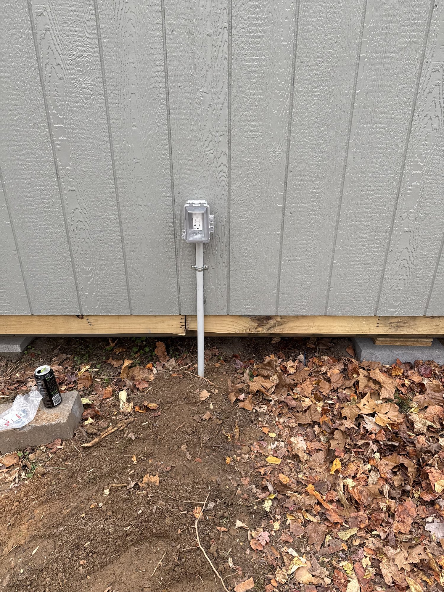 Weatherproof in-use cover GFCI receptacle and conduit riser on the exterior wall of a shed