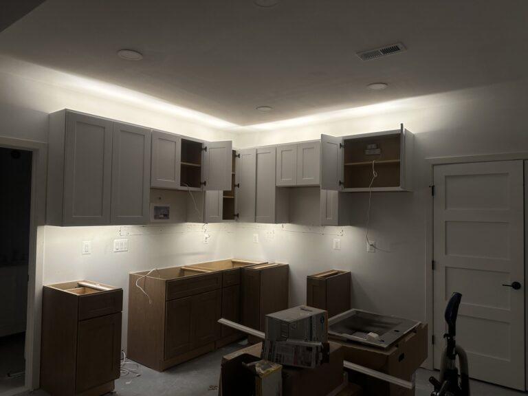 Kitchen with LED tape lighting glowing above the upper cabinets and washing the counter below