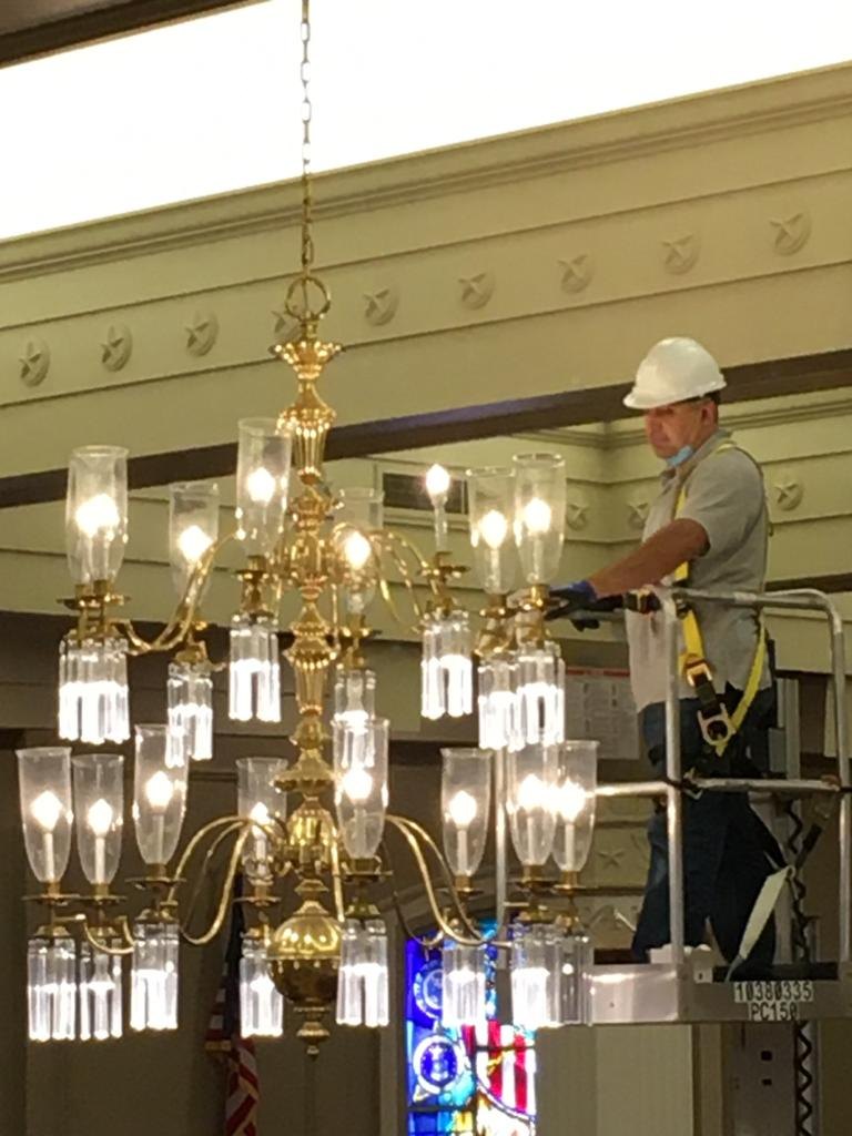 SparkWise Electric technician servicing a chandelier from a lift