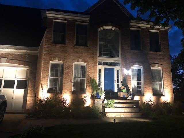 Facade uplighting on a brick home at night installed by SparkWise Electric